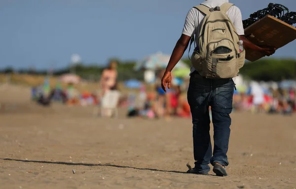 Handlarz Długimi Spodniami Spacerujący Słonecznej Plaży Chcący Sprzedać Okulary Wczasowiczom — Zdjęcie stockowe