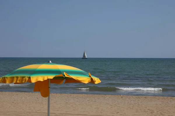 Yellow Green Umbrella Sea Sailboat Distance Summer — Fotografia de Stock