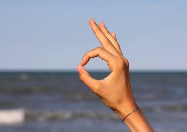 hand making OM yoga symbol with forefinger and thumb finger touching and seeming to say OK alright