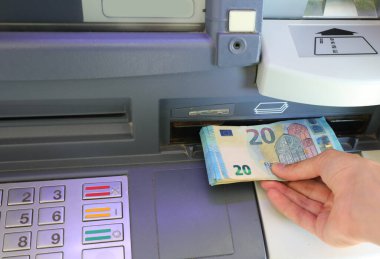 hand while withdrawing money European banknotes from an ATM cash machine