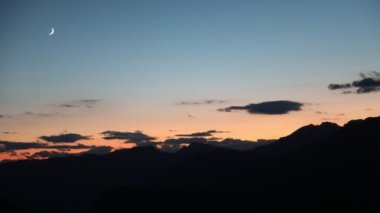 Sunset and little moon and clouds at evening in the alps