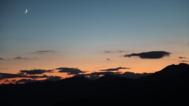 Sunset and little moon and clouds at evening in the alps