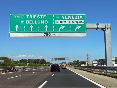 Motorway junction with large sign with directions to major cities in Italian such as Venice and the airport