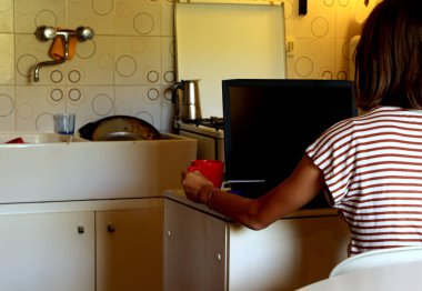 young girl in the kitchenette of the mini apartment uses the laptop