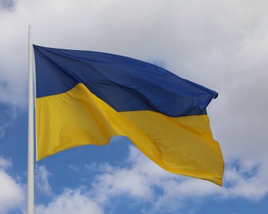 Blue and yellow flag of Ukraine with blue sky and white clouds