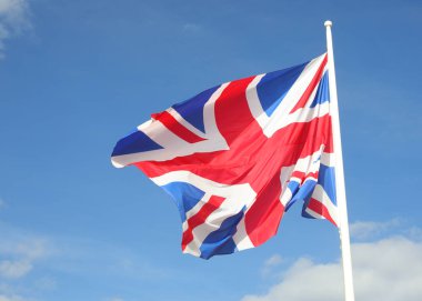 Big waving United Kingdom UK flag on blue sky background