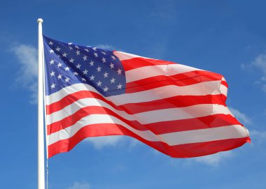 Waving big flag of United States of America on blue sky background