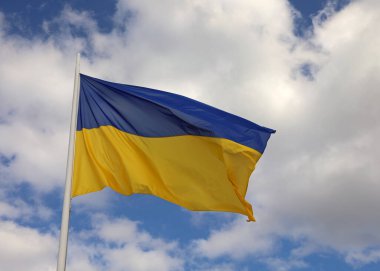 Blue and yellow flag of Ukraine with blue sky and white clouds
