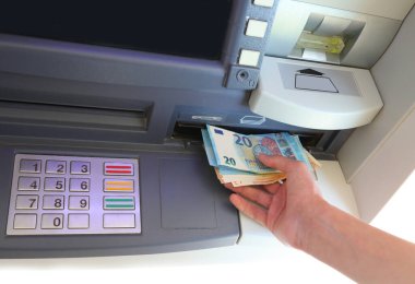 Hand taking money from cash machine and numeric keypad to enter PIN code