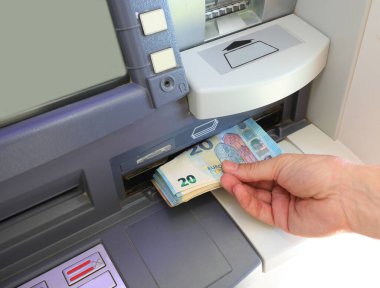 hand picking up Euros 20 banknotes on the ATM of the bank in Europe