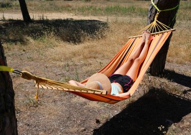 girl with straw hat sleeping relaxing on hammock in summer