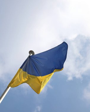 Blue and yellow flag of Ukraine with blue sky and white clouds