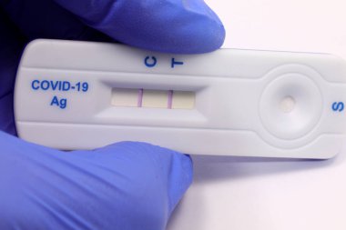Hand with latex glove and antigenic swab with the positive test for covid-19