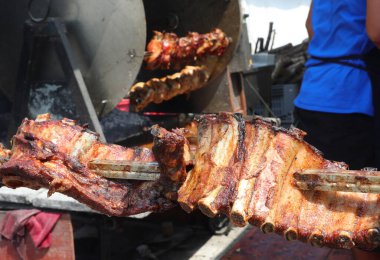 many pork ribs cooked on a spit in the large restaurant during the village festival
