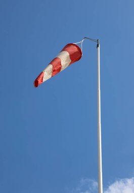 red and white windsock to indicate the direction of the air flow and the blue sky clipart