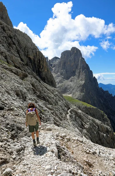 在欧洲阿尔卑斯山的白云岩高山上 背着背包的年轻女性徒步旅行者走在石路上 — 图库照片
