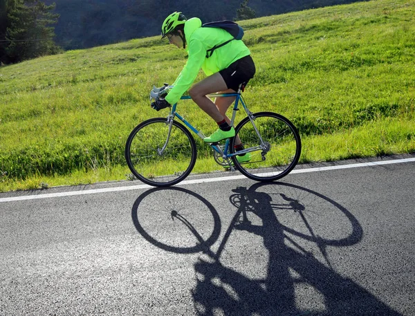 young cyclist with racing bicycle and phosphorescent waterproof jacket on a mountain road