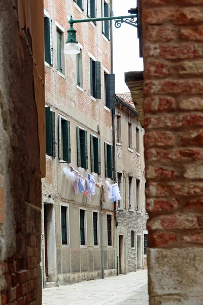 ヴェネツィアの狭い通りや人のいない家にぶら下がっている服を垣間見る — ストック写真