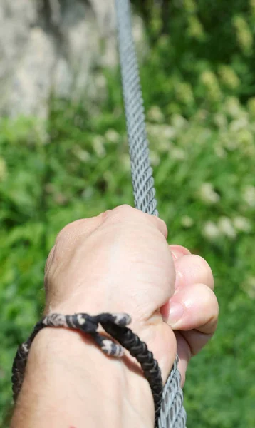 ハイキング中に山の中にしっかりとビア フェラータのロープを持っている人の手 — ストック写真