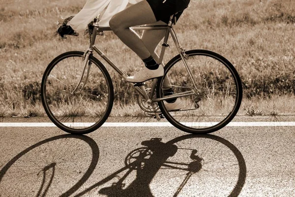 cyclist rides fast against the light with a historic racing bike on the asphalt road