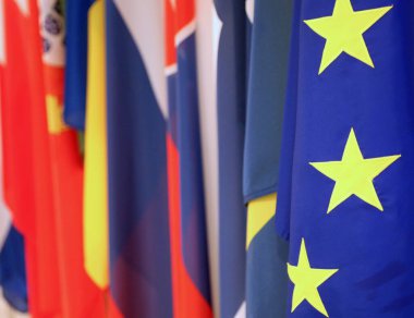 Avrupa Birliği bayrağının mavi arka planında üç sarı yıldız ve birçok uluslararası bayrak