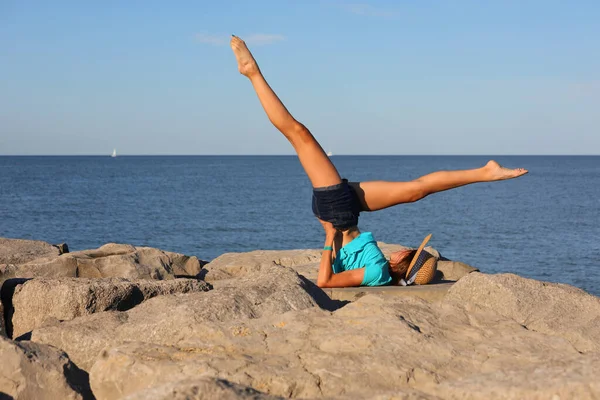 脚を持つ細い女の子は夏に岩の上で体操をします — ストック写真