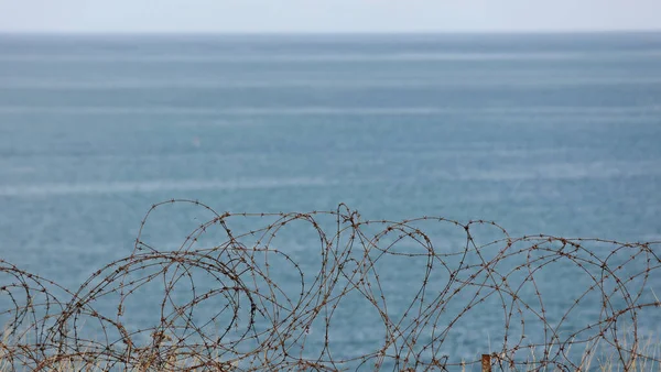 metal barbed wire from World War II with the English Channel in the background