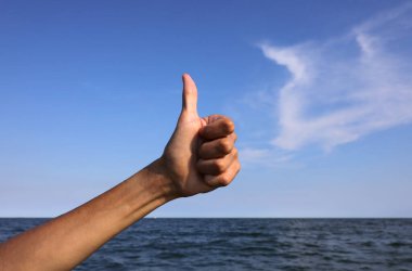 hand with thumb up pointing up ok sign all right or success and the sea