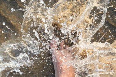 Yazın deniz suyu ve çıplak ayaklı kişinin ayağı.