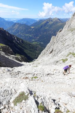 Sırt çantalı genç bir kadın Alplerdeki çakıl yolunda yürüyor.