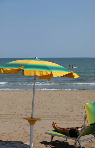 green and yellow colored sun umbrellas on the sandy beach by the sea