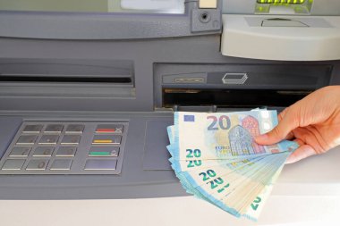 hand of the person who withdraws money in european twenty euro banknotes in the atm automatic teller machine