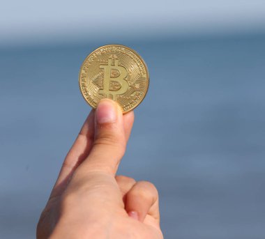 Büyük harf B ile yazılmış altın bir para ile el Kripto para birimi Bitcoin 'i sembolize ediyor