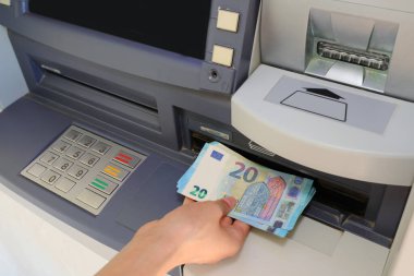 Avrupai bankanın ATM 'sinden 20 Euro' luk banknotları alan el.
