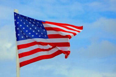 Geniş Amerikan Bayrağı mavi gökyüzünde biraz bulutla dalgalanıyor