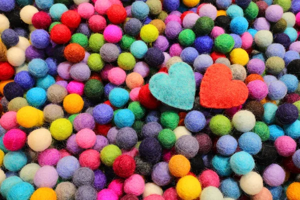 balls of carved felt wool and two blue and red hearts