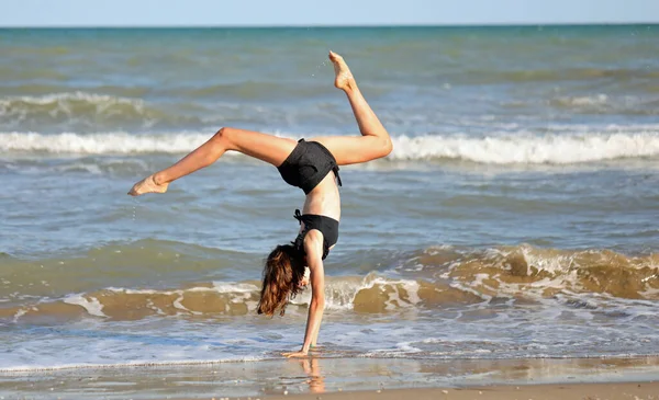 海岸での新体操の黒水着の少女 — ストック写真