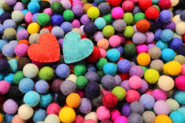 balls of carved felt wool and two blue and red hearts