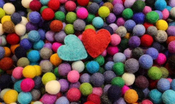 balls of carved felt wool and two blue and red hearts