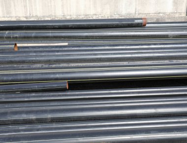 Yol inşaatındaki inşaat malzemelerinin birikintisindeki siyah plastik borular.