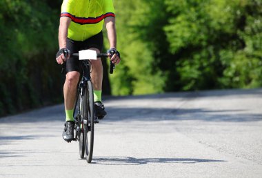 Yarış sırasında asfalt yolda motosikletli bir bisikletçi.