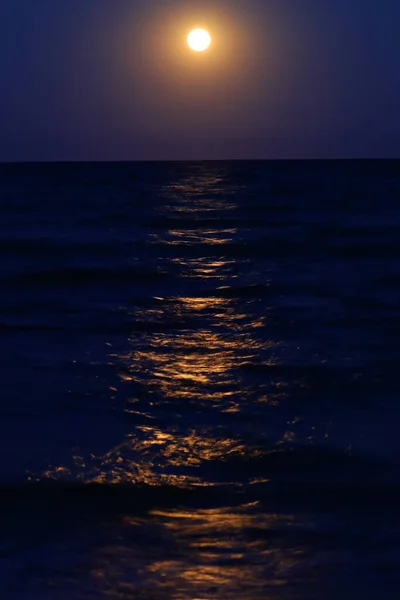 full moon rising from the sea and the reflection of light on the water