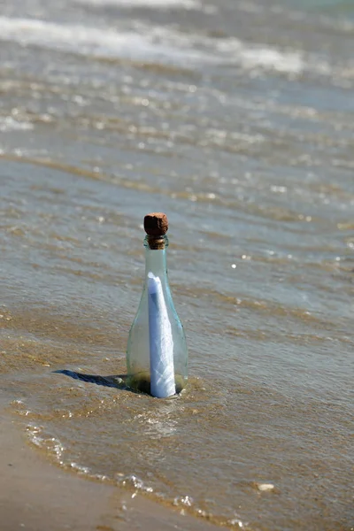 clear glass bottle with secret message inside by the sea