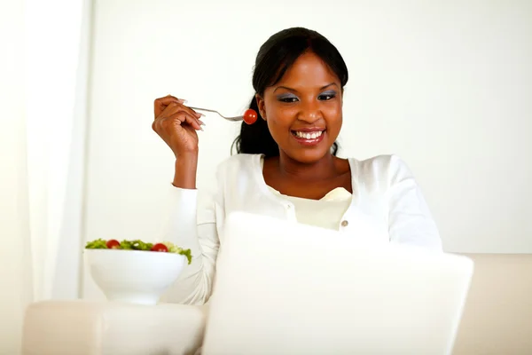 Mujer afroamericana usando laptop comiendo una ensalada —  Fotos de Stock