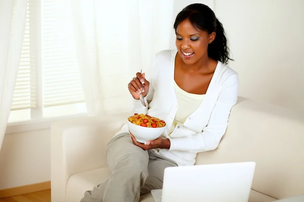 Giovane femmina che fa colazione e utilizza il computer portatile — Foto Stock