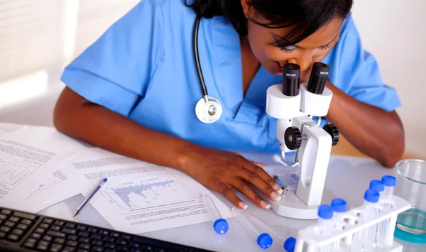 Enfermera bonita trabajando con un microscopio — Foto de Stock