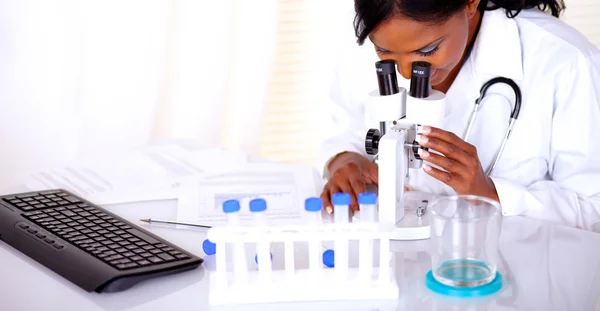 Mujer doctora encantadora usando un microscopio — Foto de Stock