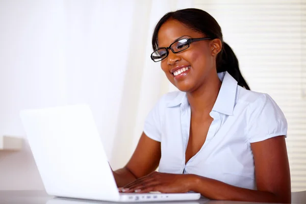 Schöne junge Frau lächelt und schaut zum Laptop — Stockfoto