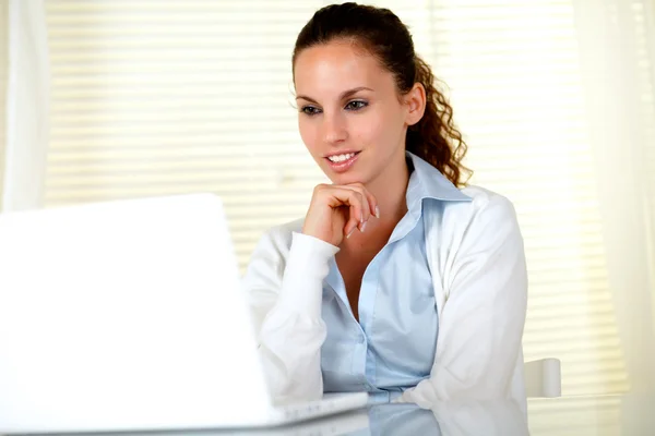 Pensivo atraente jovem do sexo feminino usando seu laptop — Fotografia de Stock