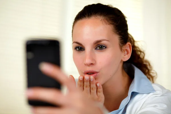 Mooie jonge vrouw zoenen naar mobiel — Stockfoto